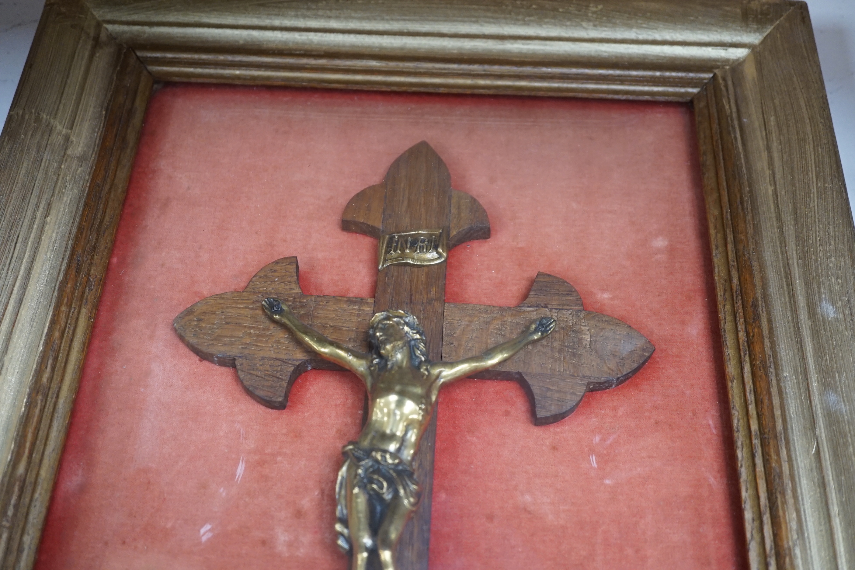 An oak and brass crucifix framed behind convex glass, overall 51cm x 37cm